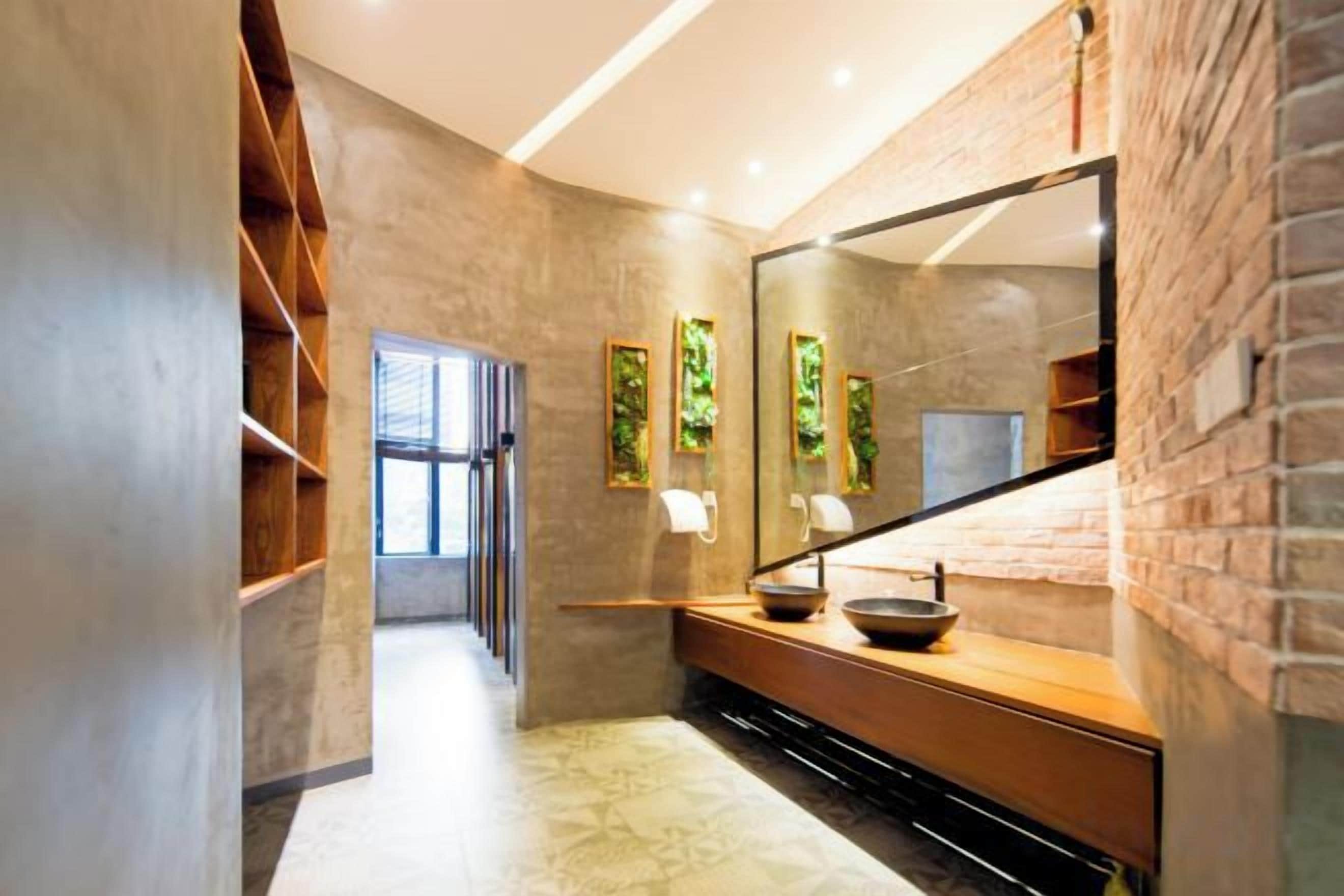 Un baño moderno con un espejo grande, tocador de madera y vistas al pasillo.