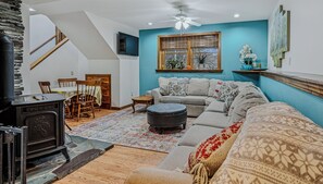 Un salon avec un canapé, un pouf et une cheminée.