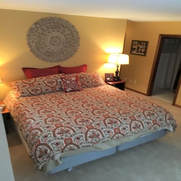 Une chambre à coucher avec un lit, une horloge murale, une lampe et un tableau encadré accroché au mur.