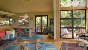 A spacious living area with a large window, a glass-top coffee table, and a colorful rug. - Modern Hillhouse with Lake Washington Views (Kirkland)