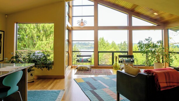 A spacious room with large windows, a dining area, and a cozy seating area. - Modern Hillhouse with Lake Washington Views (Kirkland)