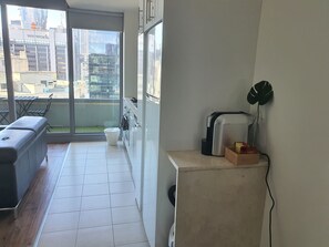 Eine moderne Wohnung mit Balkon, einer Couch, einer Küchenzeile und Blick auf die Stadt.
