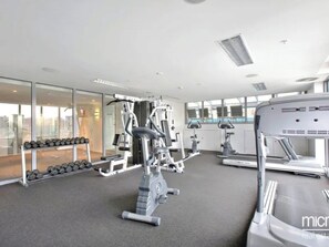 A modern gym with cardio machines, weightlifting equipment, and dumbbells.