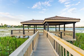 Stroll along the boardwalk to two serene gazebos overlooking a tranquil water body surrounded by lush vegetation.
