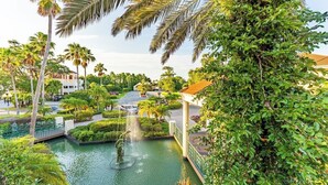 A landscaped area with a water feature, palm trees, and a building with a red roof. - Kissimmee | Family Park Trip | Pool & Sports Courts | 3BR Sleeps 8 (Kissimmee)