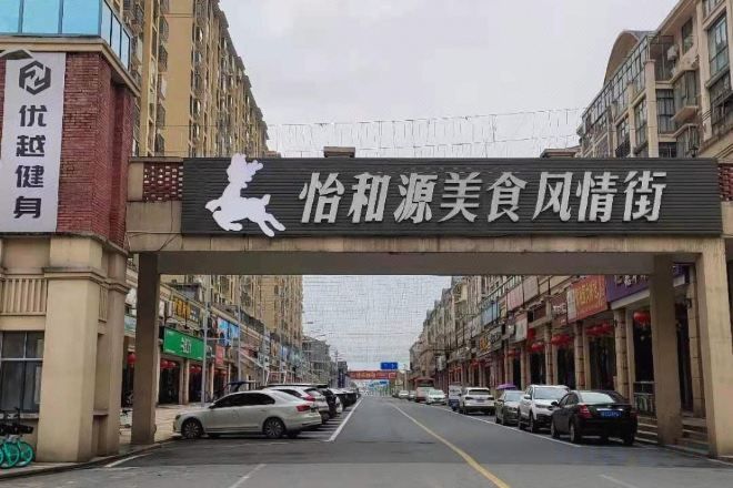 A street with a sign overhead and parked cars.