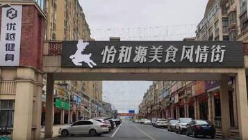 A street with a sign overhead and parked cars.