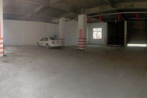 Een parkeergarage met een witte auto, geparkeerd in de buurt van een pilaar, een raam en een deur.