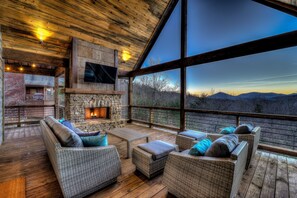 A cozy outdoor seating area with wicker furniture and a stone fireplace, overlooking a mountainous landscape. - BRAND NEW! Sunrock Mountain Dream ~ LUXURY Cabin (Blue Ridge)