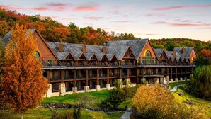 Un chalet doté de plusieurs balcons et d’une fondation en pierre, entouré d’un feuillage automnal.