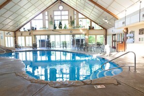An indoor swimming pool with a high ceiling, large windows, and a seating area with tables and chairs. - Wilderness Club™ at Big Cedar® - 3 Bedroom Cabin (Ridgedale)