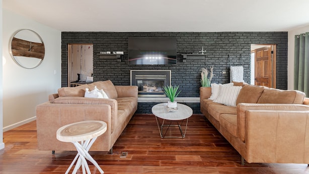 A living room with two sofas, a round coffee table, and a fireplace with a TV above it. - Tranquil Lodge with A+ Amenities (Naples)
