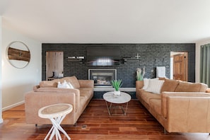 A living room with two sofas, a round coffee table, and a fireplace with a TV above it. - Tranquil Lodge with A+ Amenities (Naples)