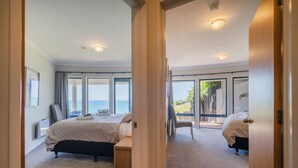 Quarto com cama, uma cadeira e vista para o mar.