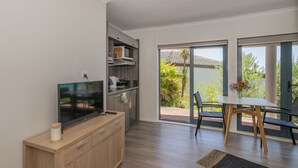Uma cozinha moderna com TV integrada, armários de madeira e uma porta de vidro deslizante para uma varanda.