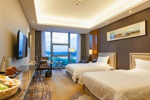 A hotel room with two beds, a desk with a chair, a TV, and a large window offering a view. - Hui Chang Hotel (Huichang)