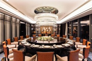 A round dining table with chairs, a chandelier, and a floral centerpiece. - Hui Chang Hotel (Huichang)