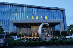 Un edificio moderno con una amplia fachada de vidrio y una llamativa escultura circular en primer plano.