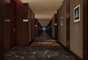 Un largo y estrecho pasillo de hotel con paredes de madera y suelo alfombrado.