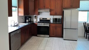 Une cuisine avec des meubles en bois, des appareils électroménagers en acier inoxydable et un sol carrelé.