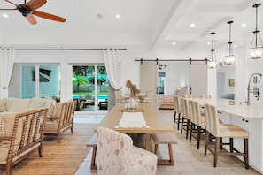 A spacious living area with a long dining table, comfortable seating, and a ceiling fan. - Seabreeze 30A: Luxe 5BR w/ Pool & Beach Access (Rosemary Beach)