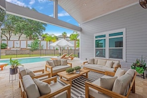 A covered patio with outdoor furniture, a pool, and a view of the neighborhood. - Seabreeze 30A: Luxe 5BR w/ Pool & Beach Access (Rosemary Beach)