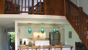 A spacious living area with a kitchen, a dining set, and a staircase leading to an upper level. - Kraken Cove St. Croix (Sion Farm)