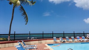 Ein Poolbereich mit Liegestühlen, einem Schwimmbecken und Blick auf den Ozean.