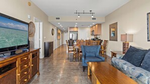 A spacious living area with a television, wooden furniture, a ceiling fan, and a dining area with chairs and a table. - Sterling Breeze 2Bd/3Ba w/Bunk Room / Near Pier Park /Sleeps 8 (Panama City Beach)