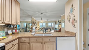 A kitchen with wooden cabinets, a granite countertop, and a dishwasher.