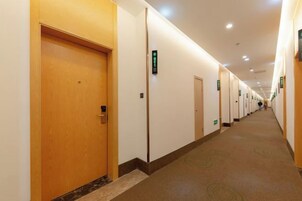 Un pasillo de hotel con puertas, pisos alfombrados e iluminación en el techo.