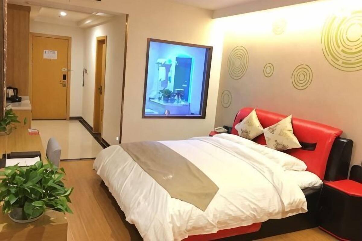 A hotel room with a bed, a desk, a chair, and a TV screen.