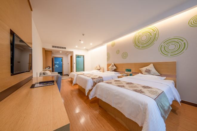 Habitación de hotel con dos camas, un escritorio, un televisor y una pared con diseños circulares.