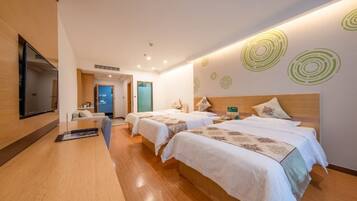 Habitación de hotel con dos camas, un escritorio, un televisor y una pared con diseños circulares.