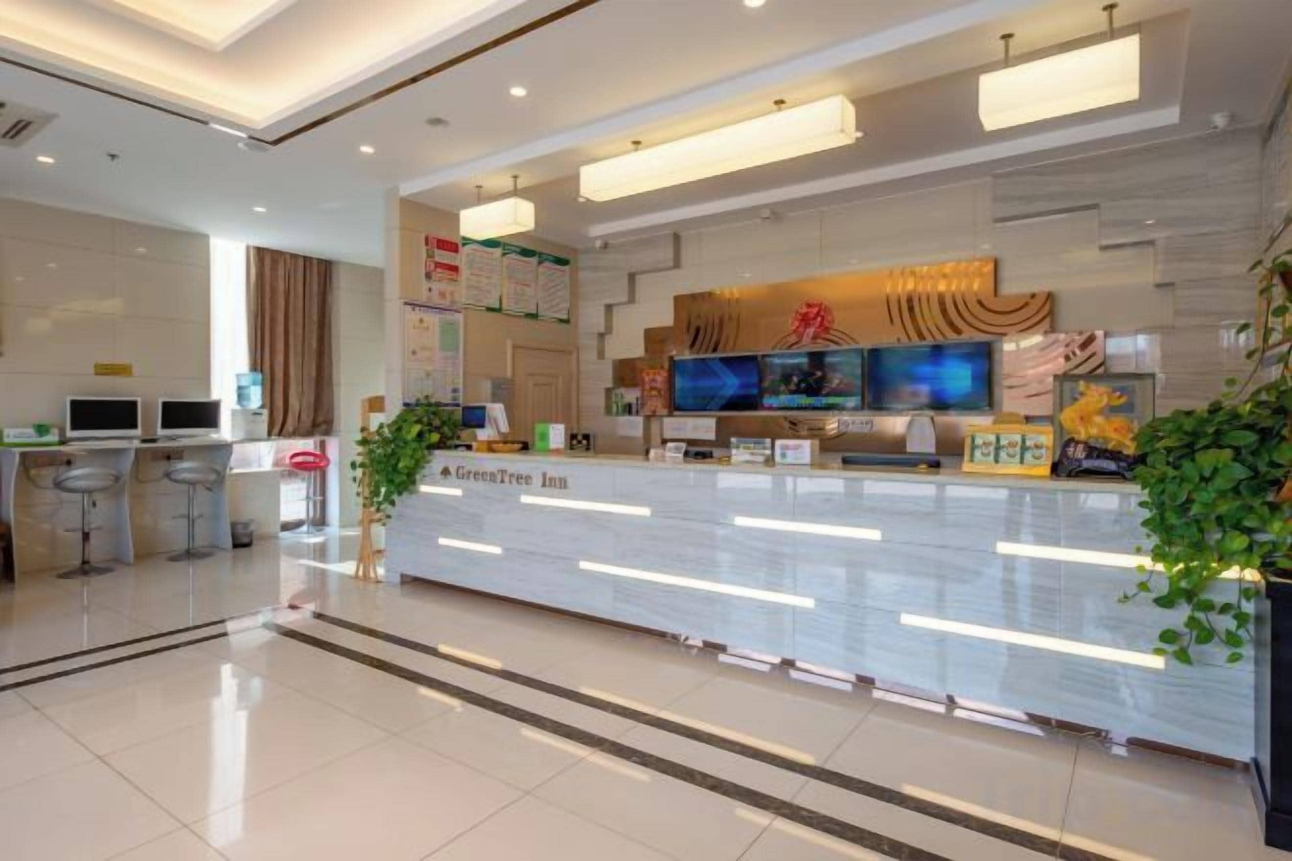 A hotel reception area with a modern design, a reception desk, and a seating area with bar stools.