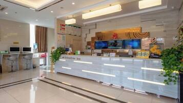 A hotel reception area with a modern design, a reception desk, and a seating area with bar stools.
