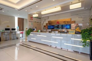 A hotel reception area with a modern design, a reception desk, and a seating area with bar stools. - GreenTree Hotel (Nantong University International Exhibition Center) (Nantong)