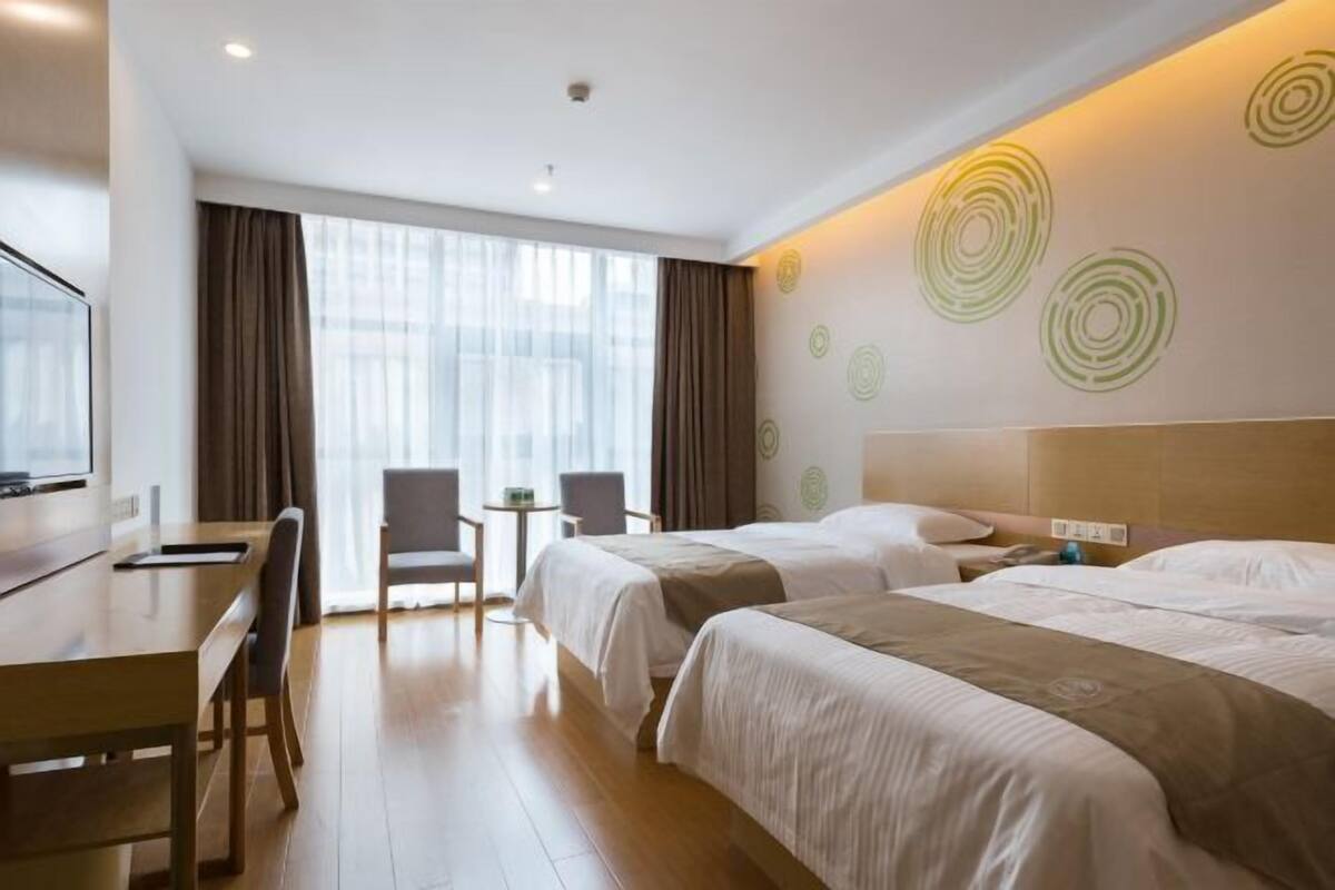 A hotel room with two beds, a desk, and a chair.
