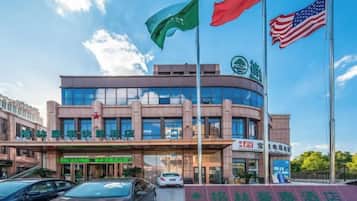Un hotel con una fachada moderna, varias banderas y un cielo despejado.