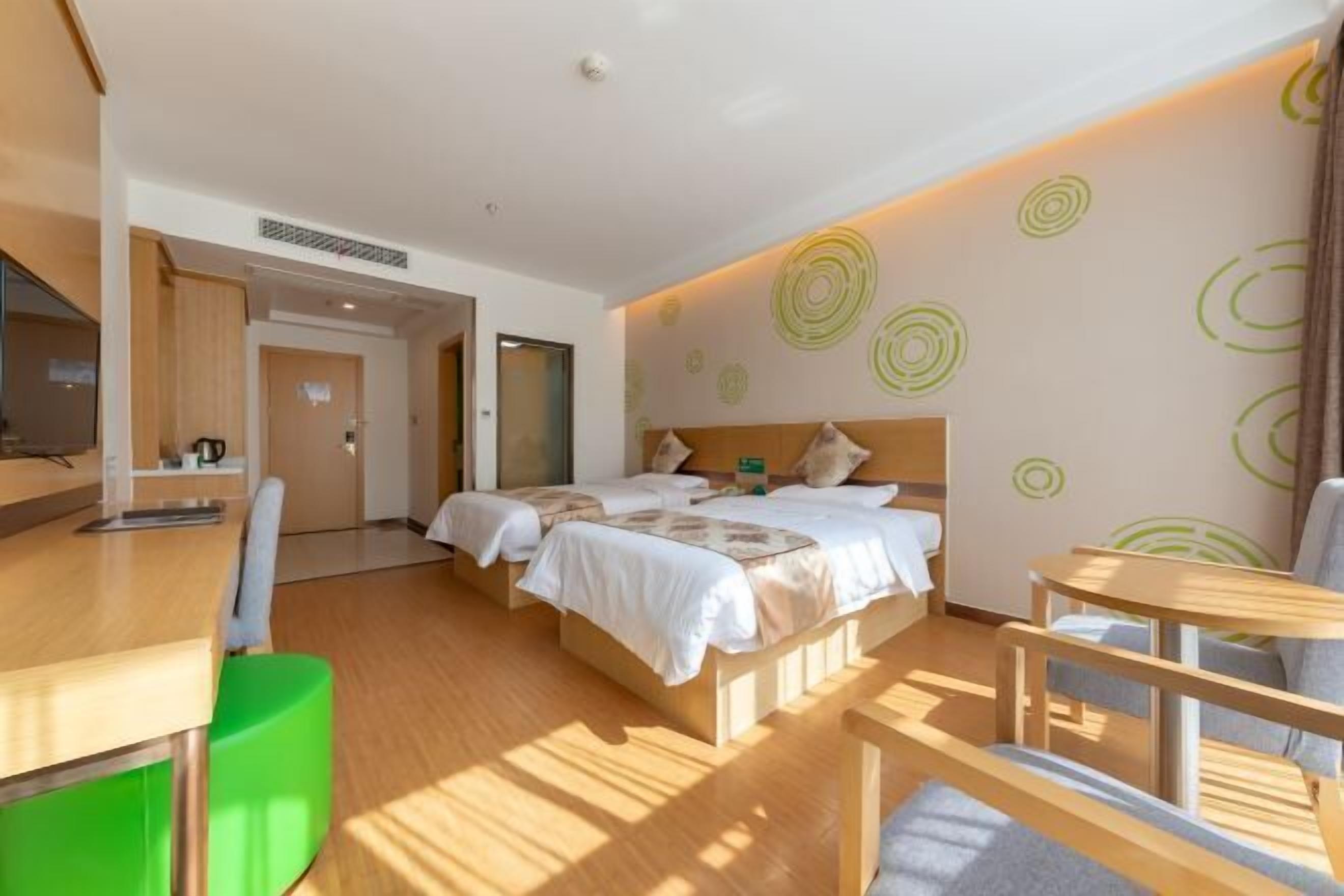 A hotel room with two beds, a desk, a chair, and a small table.