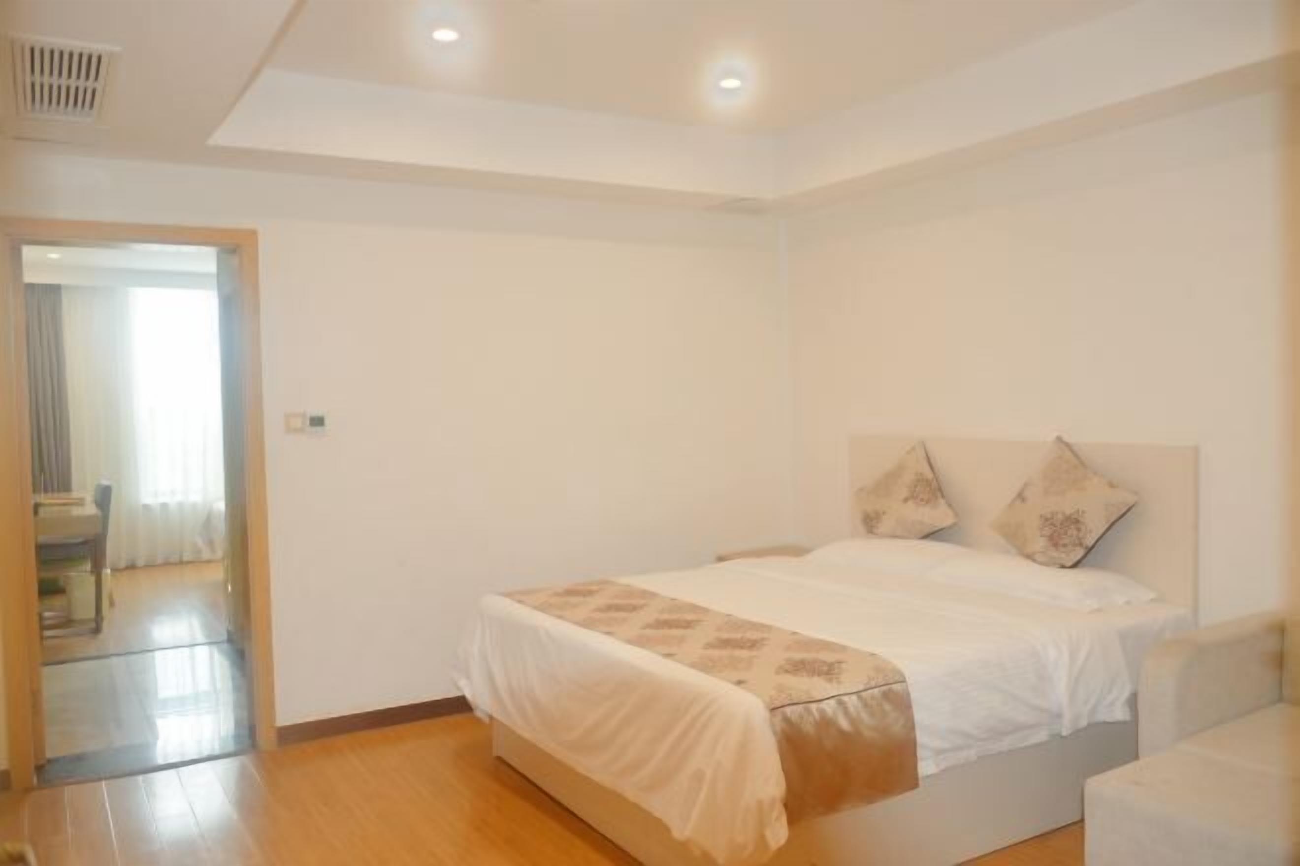Un dormitorio con una cama, una mesita de noche y una puerta que da a otra habitación.