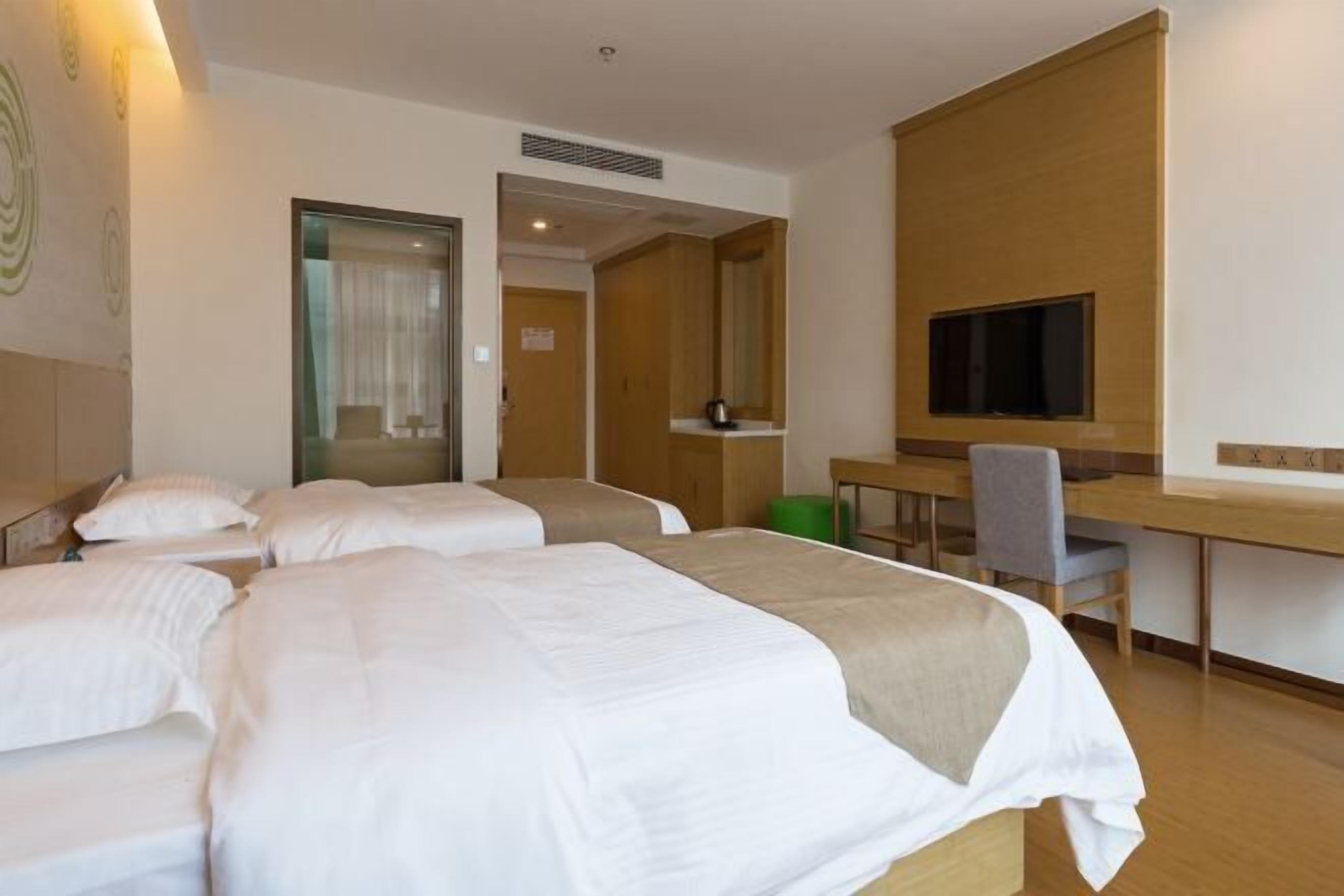 A hotel room with two beds, a desk, a chair, a television, and a mirror.