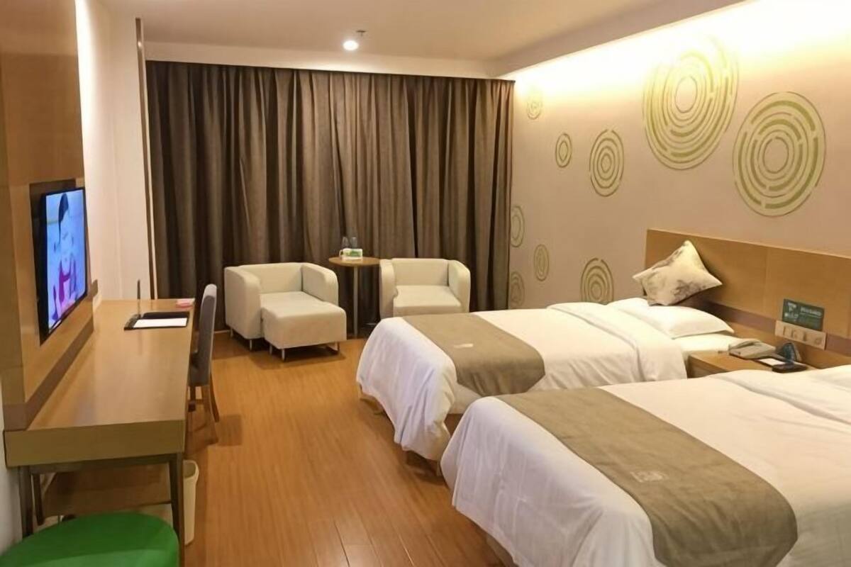 A hotel room with two beds, a desk, a chair, a TV, and a curtain.