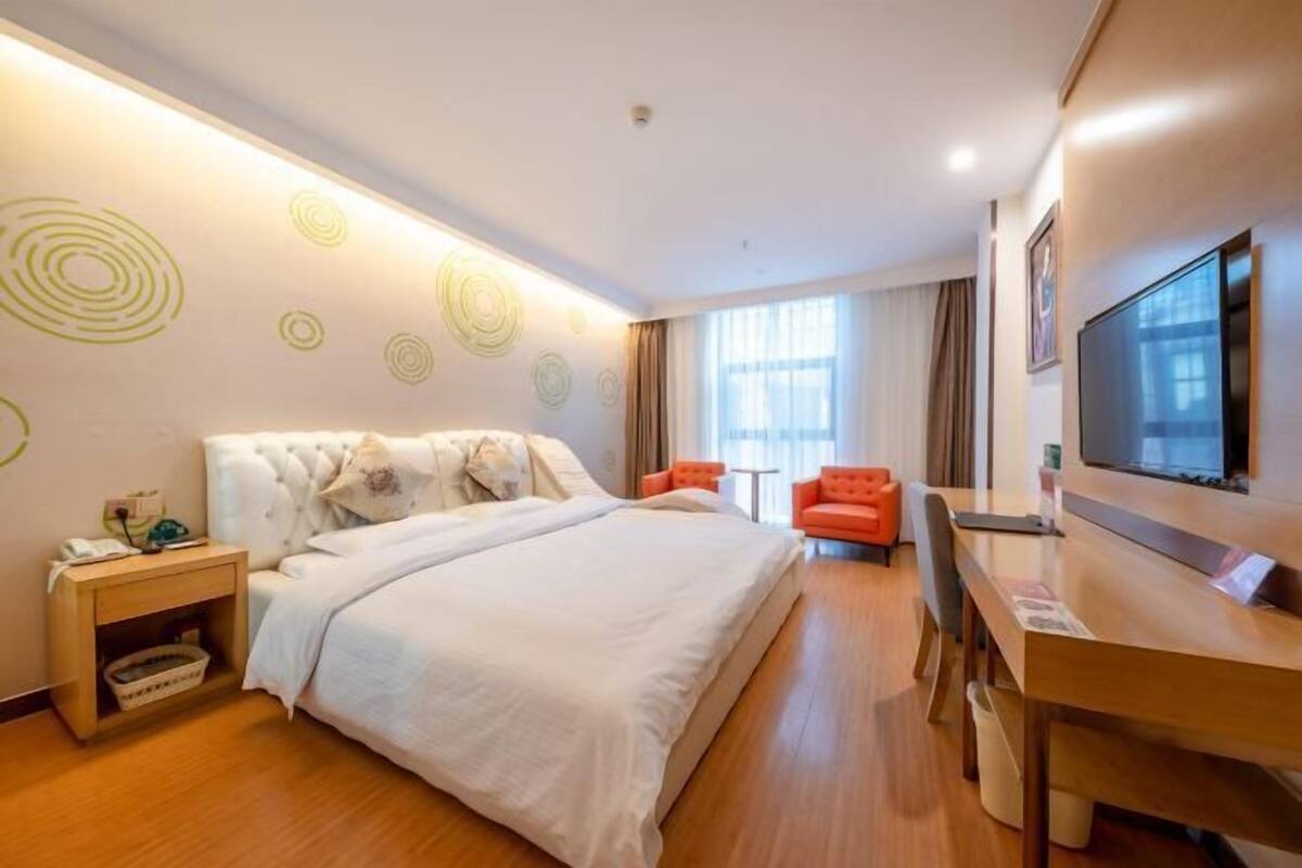 A hotel room with a bed, a desk, a TV, a chair, and a window.