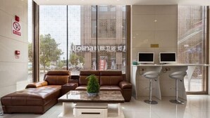 A modern living room with a brown leather sofa, a coffee table, and two bar stools. - GreenTree Hotel (Nantong University International Exhibition Center) (Nantong)