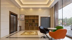A lobby with a reception desk, a seating area with chairs, a patterned rug, and a wall-mounted shelf with plants. - GreenTree Hotel (Nantong University International Exhibition Center) (Nantong)