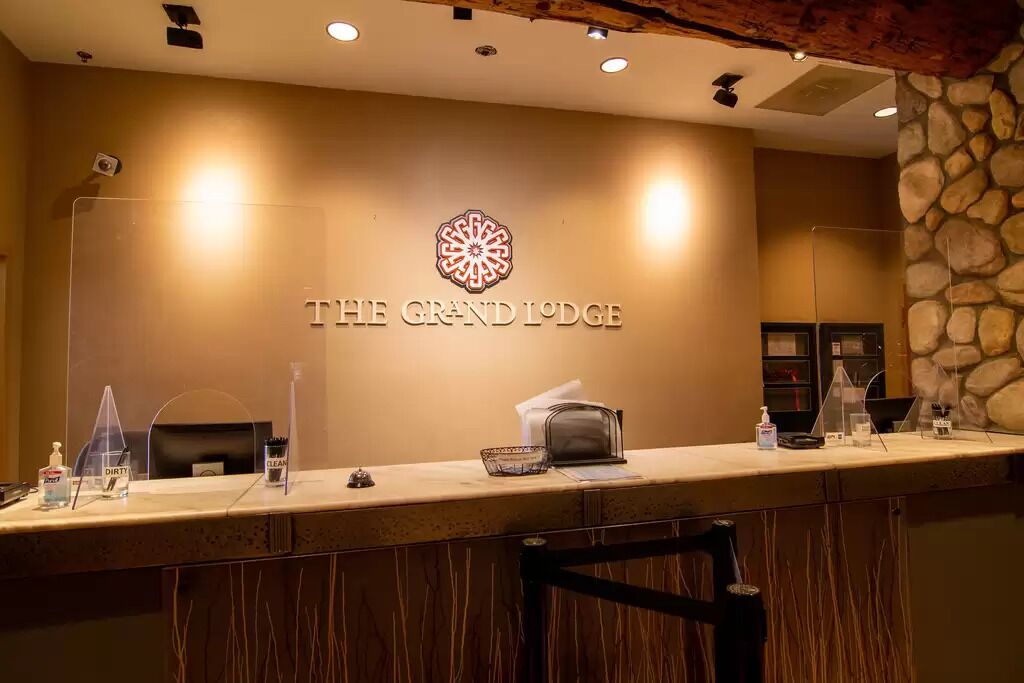 A reception desk with a sign reading "THE GRAND LODGE" and a logo above it.