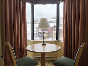 Enjoy a cozy stay in this inviting room with a round table, comfortable chairs, and a large window offering a scenic view.