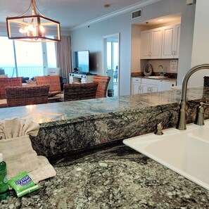 A kitchen with granite countertops, a stainless steel sink, and white cabinets.