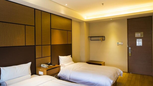 A hotel room with two beds, a bedside table with a phone, a nightstand, a door, and a wall-mounted shelf. - Ji Hotel Shanghai Songjiang Sports Square Center (Shanghai)